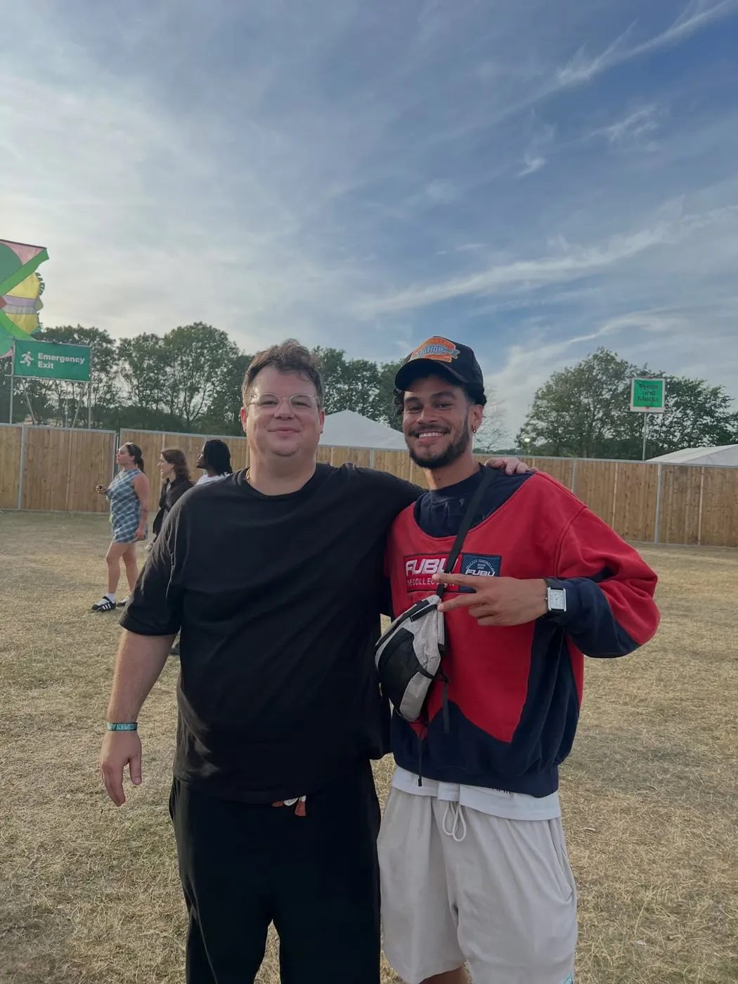 Osk and a friend posing together in a festival field under a big sky.